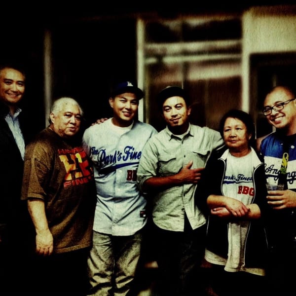 Six smiling people, including three men in "The Park's Finest" shirts, pose together.
