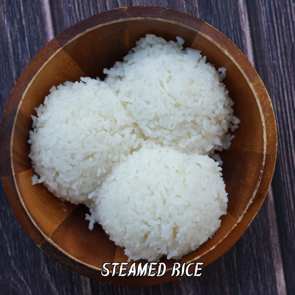 Three mounds of white steamed rice in a wooden bowl on a dark wooden table.