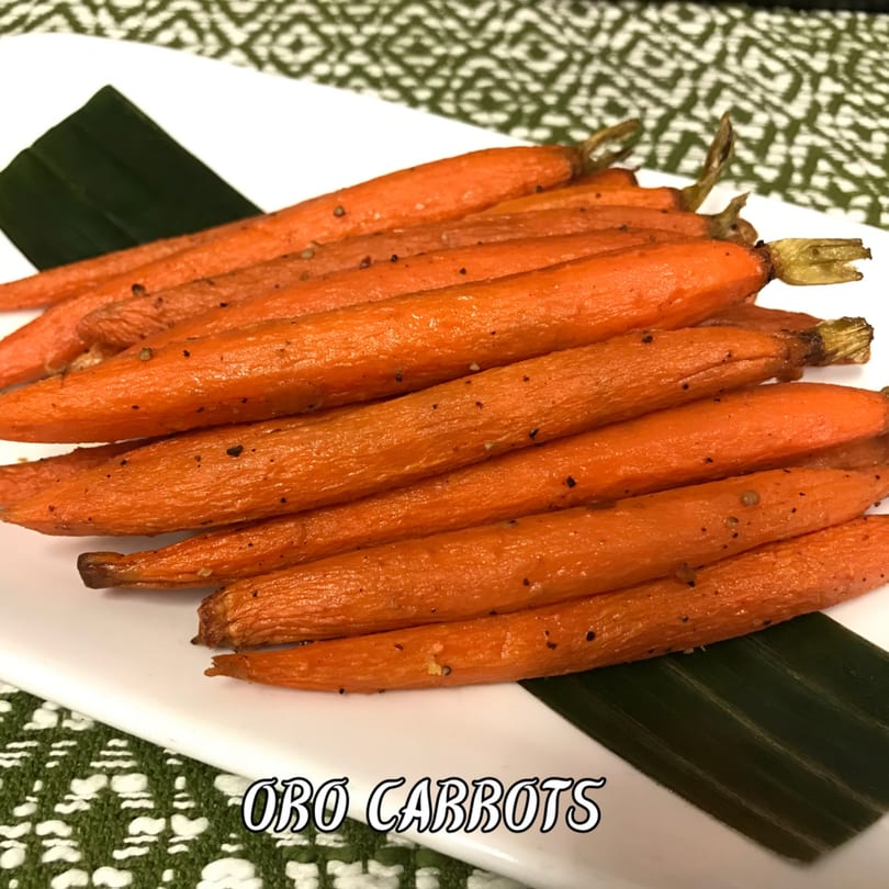 A serving of ORO Carrots, glazed and seasoned, presented on a white plate with a dark green leaf.