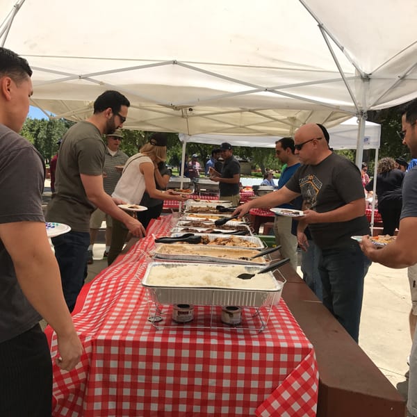 People serving themselves Filipino food from a buffet line under a white tent at The Park's Finest.