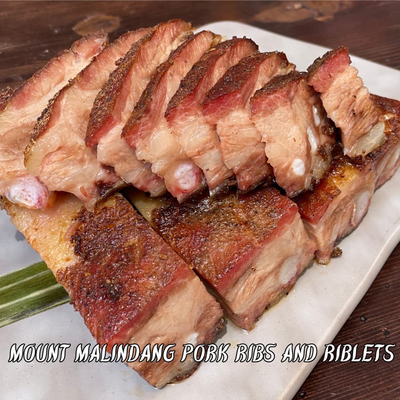 Sliced Mount Malindang pork ribs and riblets, showing crispy skin and juicy meat on a white plate.