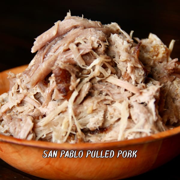 Close-up of tender San Pablo pulled pork piled high in a wooden bowl.