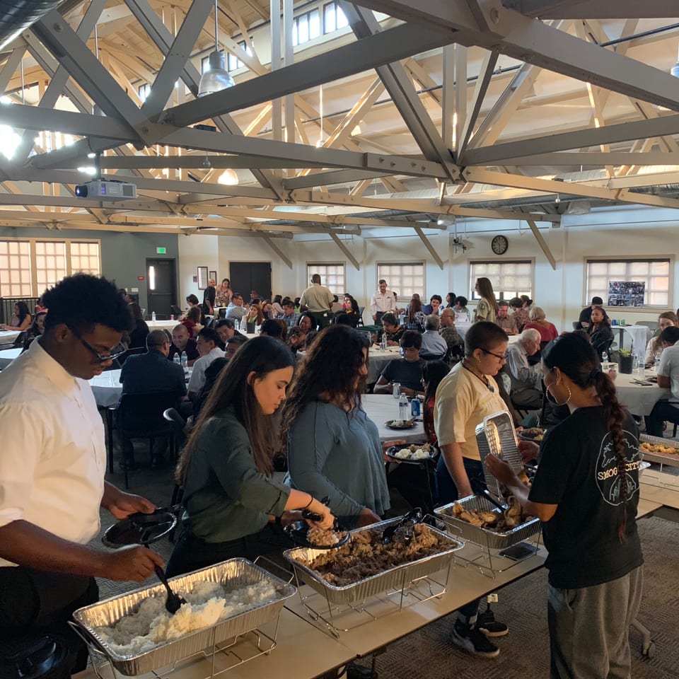 Guests at The Park's Finest buffet line serving themselves Filipino food in a large hall.